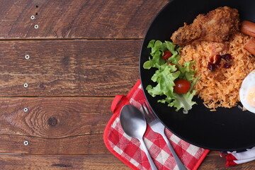 American fried rice served with sausages, cucumbers, shredded vegetables in a gray plate on a white table with seasoning.