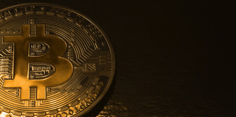 Gold bitcoin coin close up with copy space. Banner with a bitcoin coin on the side of the image