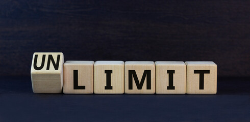 Limit or unlimit symbol. Turned wooden cubes and change the concept word Limit to Unlimit. Beautiful black table black background. Business limit or unlimit concept. Copy space.