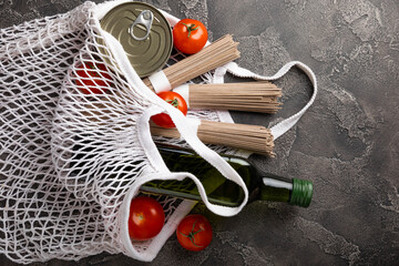 Ecobag with a grocery set. White string bag, shopper. Buckwheat sobo, cherry tomatoes, olive oil and canned meat. Shopping concept. Healthy food. Purchases.