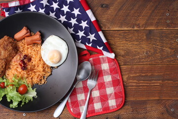 American fried rice served with sausages, cucumbers, shredded vegetables in a gray plate on a white table with seasoning.