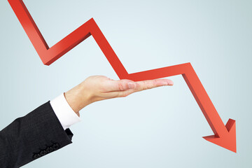 Crisis insurance concept with man hand against falling down red arrow on abstract light background