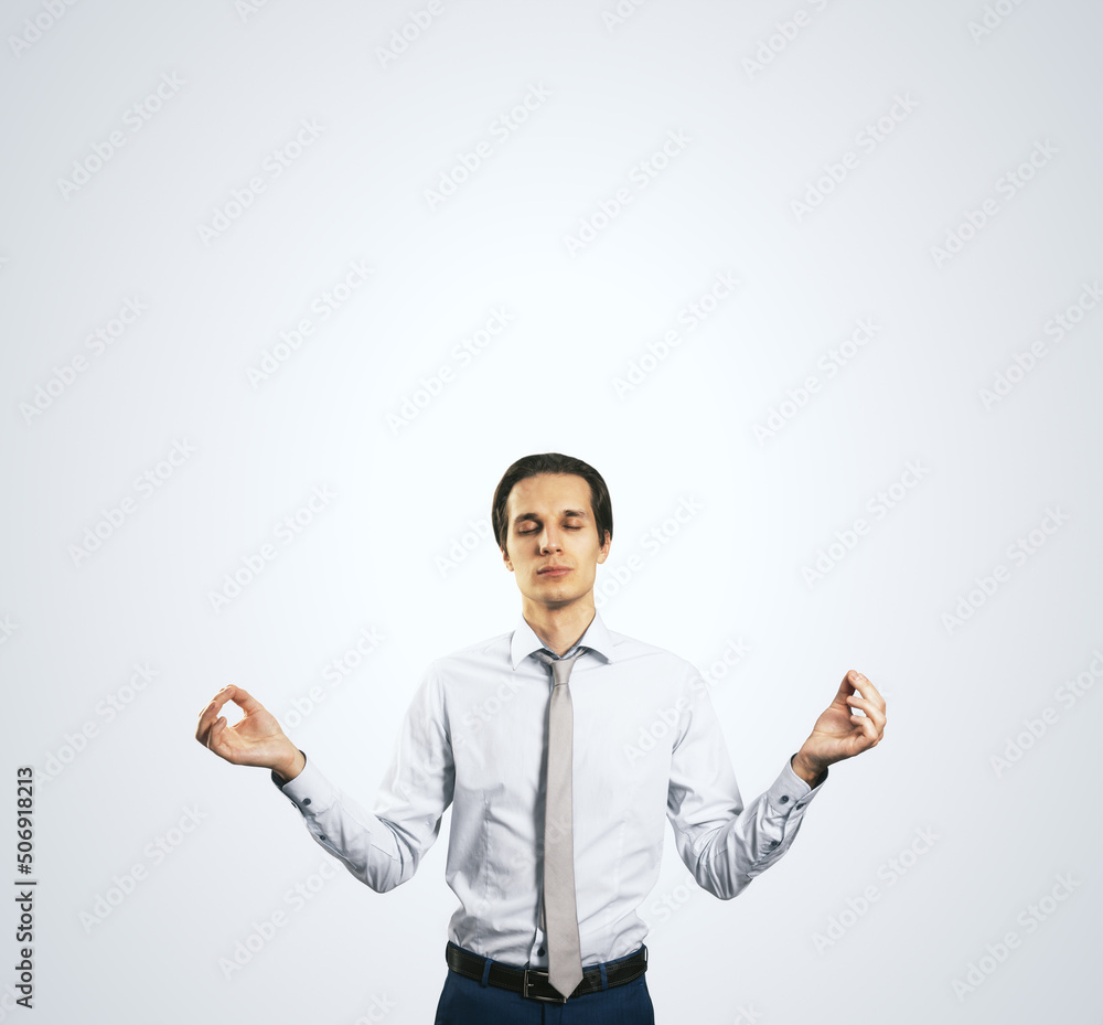 Poster calm down concept with man in white shirt in a zen pose isolated on light grey wall background with 
