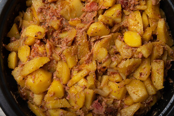 Braised pork with potatoes and onions on a brown textured wood. Copy space. Place for text. Fried potato recipe.