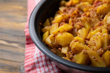 Braised pork with potatoes and onions on a brown textured wood. Copy space. Place for text. Fried potato recipe.