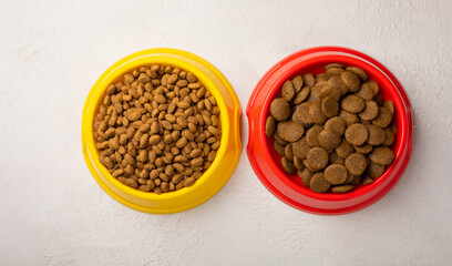 Dry food for cats and dogs in a yellow and red bowl on  cement background.Vitamins and nutrients for good health and pet energy.