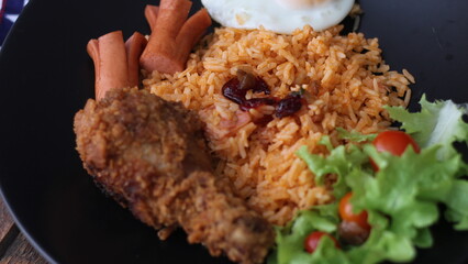 American fried rice served with sausages, cucumbers, shredded vegetables in a gray plate on a white table with seasoning.