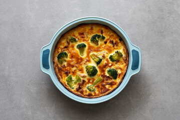 Homemade quiche with chicken, broccoli and cheese on a concrete background. Top view