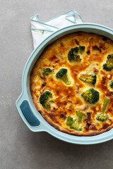 Homemade quiche with chicken, broccoli and cheese on a concrete background. Top view