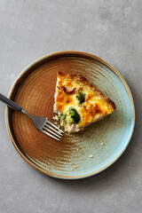 Slice of homemade quiche with chicken, broccoli and cheese on a concrete background. Top view