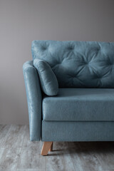 Beautiful vintage blue sofa stands on the wooden floor near the beige wall in the living room. A relaxing and comfortable sofa. Stylish interior
