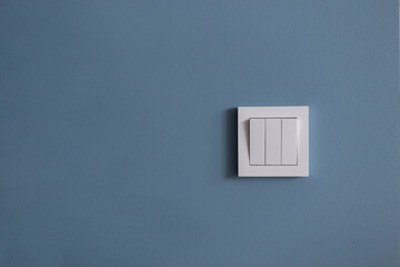 White light switch on blue wall. Free space for design and text. Creative idea - turn on