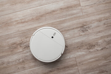 Smart robot vacuum cleaner cleans houses on a wooden floor, top view