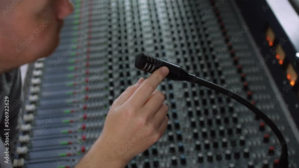 Poster a recording studio engineer music producer talking into a talkback microphone on a mixing desk conso