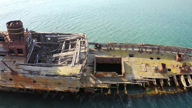 Abandoned wooden hunting schooner Lakhtak built in 1953 in Vityaz Bay. A wrecked wooden ship lies on the seashore, covered with rust. Drone view