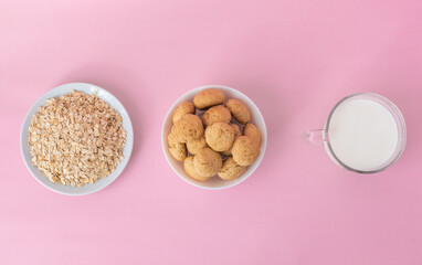 Flatlay atmeal, oatmeal cookies on a white plate, milk in transparent glass on a pink background, top view, the concept of healthy eating and making cereal or cookies. High-quality photo