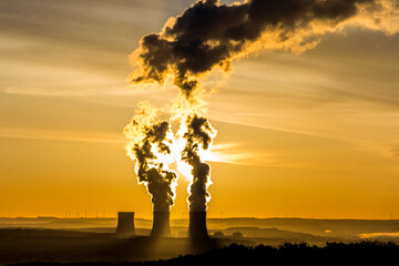 réacteurs de centrale nucléaire crachant sa fumée, au lever du soleil. prise de vue lointain sur...