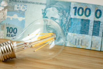 Brazilian 100 Reais and a light bulb, Concept of rising energy and electricity prices in Brazil