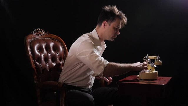 a man in a white shirt and trousers on a black background is talking on a Soviet telephone, after which he hangs up, opens the locker and takes out the key