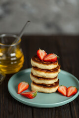 Fresh pancakes laid out in a stack, decorated with fresh berries, sprinkled with powdered sugar, beautiful serving