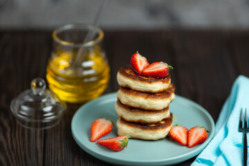 Fresh pancakes laid out in a stack, decorated with fresh berries, sprinkled with powdered sugar, beautiful serving