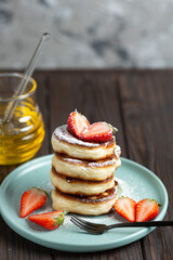 Fresh pancakes laid out in a stack, decorated with fresh berries, sprinkled with powdered sugar, beautiful serving