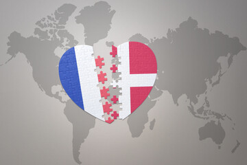 puzzle heart with the national flag of france and denmark on a world map background. Concept.
