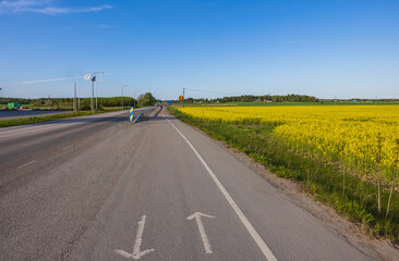 Beautiful view of bike path leading along highway on one side and rapeseed field on other. Sweden.