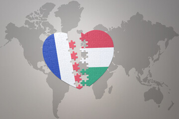 Fototapeta premium puzzle heart with the national flag of france and hungary on a world map background. Concept.