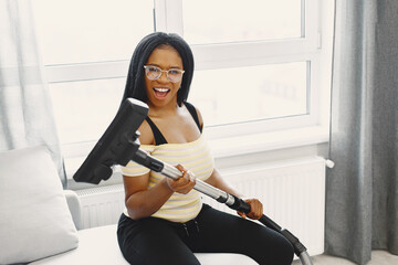 African american woman using vacuum cleaner at home