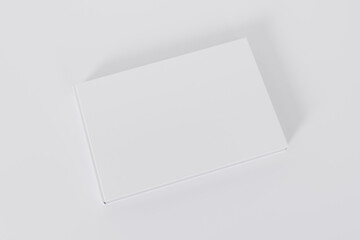 Mockup of a rectangular book with a blank glossy white cover on white background. Isolated with clipping path.	