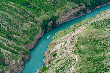 Fototapeta na wymiar mountain landscape with a deep canyon with a blue river along which a motor boat moves