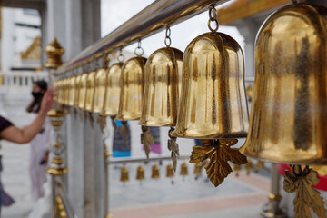 Fototapeta na wymiar Outdoor scenery at temple in Bangkok, Thailand, and selective focus view row of hanging antique brass bells, traditional religious instrument for asian and buddhism culture.