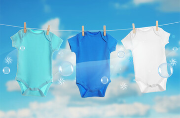 Colorful baby onesies hanging on clothes line and washing powder bubbles against cloudy sky