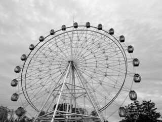 Ferris wheel or Ferris wheel is a mechanical attraction in the form of a large vertically mounted wheel, to the rim of which cabins for passengers are attached. Black and white photo