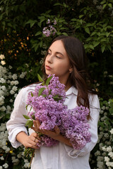 Attractive young woman with lilac flowers outdoors