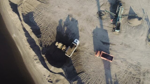 Aerial top view of trucks and machinery in the sand quarry. Scene. Sand pit, loading wagon sand, concept of heavy industry.