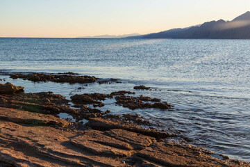 Stony ground of the coast in Lagoon beach, the Red Sea and mountains on the horizon. Dahab, South Sinai Governorate, Egypt