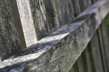 Old fence made of dry gray boards. Texture background, abstraction from the rays of the sun through the fence.