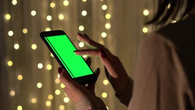 Woman holding chroma Key green screen smartphone. Mockup for browsing internet, watching content