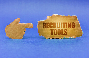 On a blue surface, a cardboard hand points to a sign with the inscription - Recruiting Tools