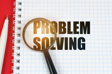 On the red surface is a pen, a notepad with the inscription - PROBLEM SOLVING and a magnifying glass
