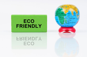 On a reflective surface is a globe and a green sign with the inscription - ECO FRIENDLY
