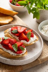 Bruschetta with goat cheese or ricotta witn strawberry and basil. Appetizer with berries. Summer healthy breakfast. Selective focus.