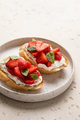 Bruschetta with ricotta, strawberries and basil on light background. Comfort food. Copy space. Selective focus.