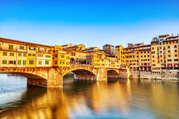 Fototapeta na wymiar Golden Sunset over Ponte Vecchio Bridge with Reflection in Arno River, Florence