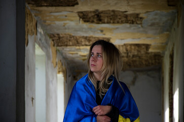 War in Ukraine. The woman is wrapped in the Ukrainian flag. Ukrainian woman in a bomb shelter. A...
