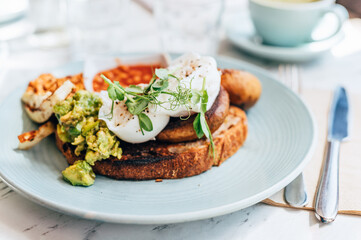 Healthy breakfast from poached eggs, grilled halloumi, scrambled smoked harissa tofu, smashed avocado, grilled mushrooms and tomato beans on toast