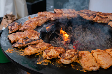 Process of cooking fresh juicy meat steaks on brazier at summer local food market - close up view. Outdoor cooking, gastronomy, cookery, street food concept