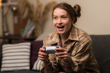 A girl with a gamepad plays a video game online with friends. Rejoices to win, emotionally reacts. Communications, new digital technologies, youth culture, competitions, tournaments, battles.